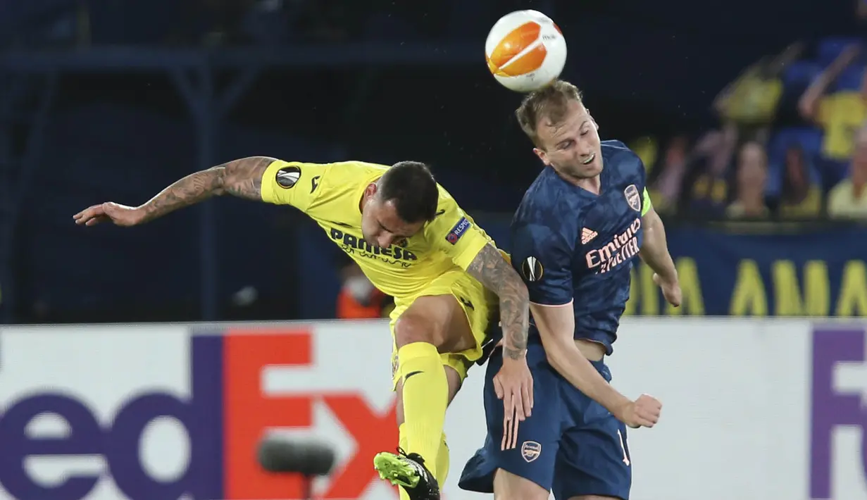 Penyerang Villareal, Paco Alcacer, duel udara dengan pemain Arsenal, Rob Holding, pada laga Liga Europa di Stadion Ceramica, Jumat (30/4/2021). Villareal menang dengan skor 2-1. (AFP/Jose Jordan)