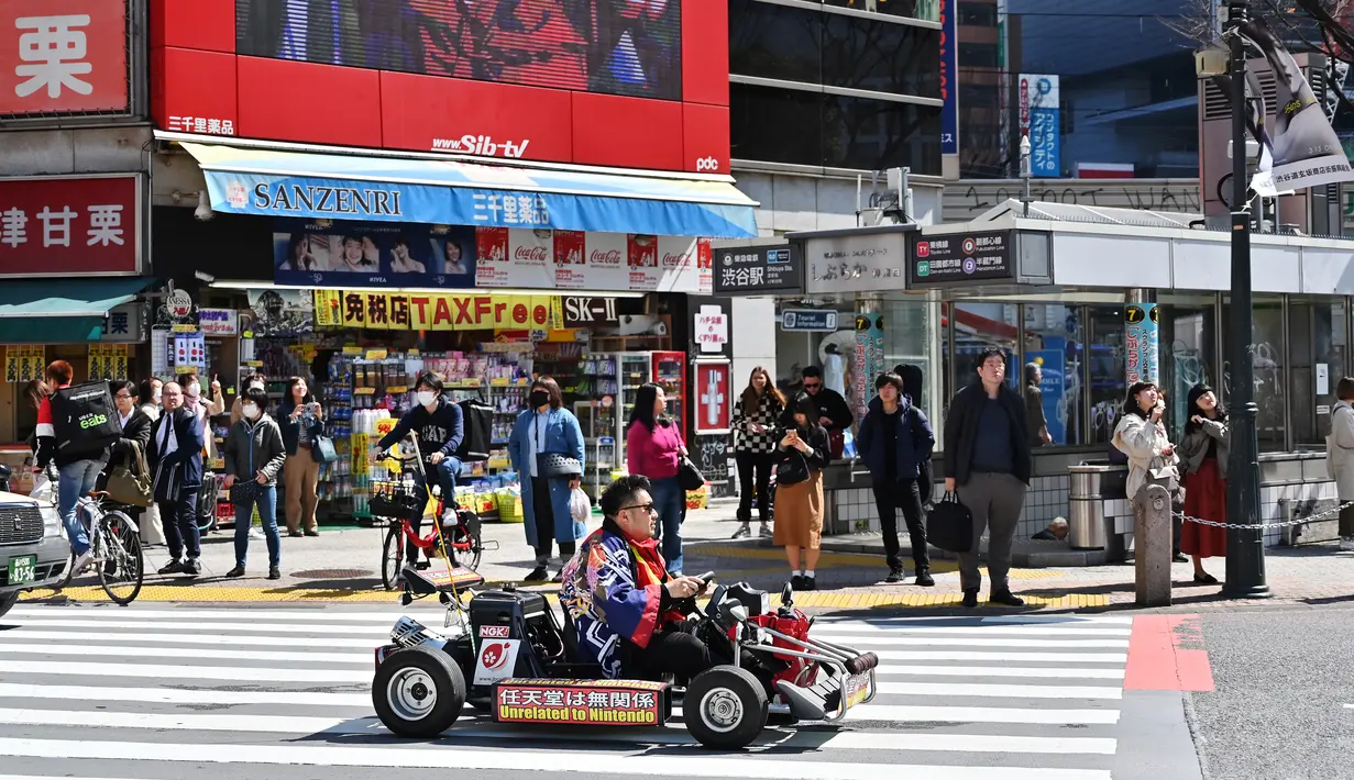 Seorang pria mengendarai go-kart di distrik Shibuya, Tokyo pada 20 Maret 2019. Persimpangan jalan ini menjadi salah satu persimpangan terbesar dan tersibuk di dunia. (Photo by CHARLY TRIBALLEAU / AFP)