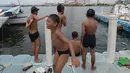Anak-anak bermain di kawasan Muara Angke, Jakarta, Sabtu (10/4/2021). Lahan tepi dermaga Kali Adem dimanfaatkan bagi anak-anak pesisir untuk bermain di area kapal bersandar. (merdeka.com/Imam Buhori)
