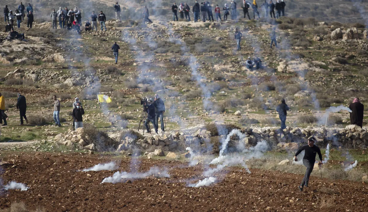 Demonstran Palestina lari dari gas air mata yang ditembakkan oleh pasukan Israel selama protes terhadap permukiman Israel, di desa Deir Jarir Tepi Barat, utara Ramallah, Jumat (1/1/2021). (AP Photo/Majdi Mohammed)