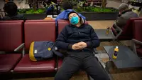 Pelancong memakai masker saat tidur siang di Bandara Internasional Ibu Kota Beijing, 23 Januari 2020. China pada Kamis (23/1) menutup sebuah kota berpenduduk lebih dari 11 juta orang dalam upaya memerangi wabah virus corona, tindakan yang belum pernah terjadi sebelumnya.  (AP/Mark Schiefelbein)
