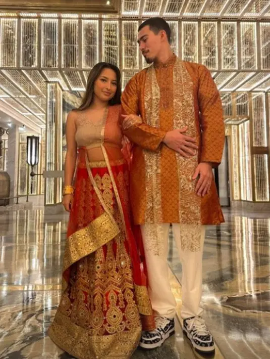 Jennifer Coppen tampil serasi dengan sang suami dalam balutan kain sari India nuansa merah keemasan. Atasan cokelat dipadukannya dengan rok dan selendang merah dengan bordir keemasan yang cantik. [Foto: Instagram/jennifercoppenreal20]