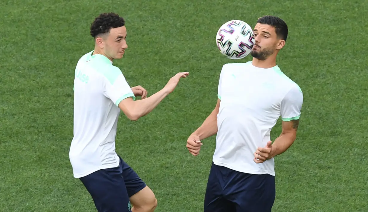 Pemain timnas Swiss, Ruben Vargas (kiri) dan Loris Benito (kanan) ambil bagian dalam sesi latihan MD-1 mereka di National Arena Bucharest, Minggu (27/6/2021). Pertandingan babak 16 besar EURO 2020 akan mempertemukan Prancis vs Swiss pada Selasa (29/6) dini hari. (Daniel MIHAILESCU/POOL/AFP)