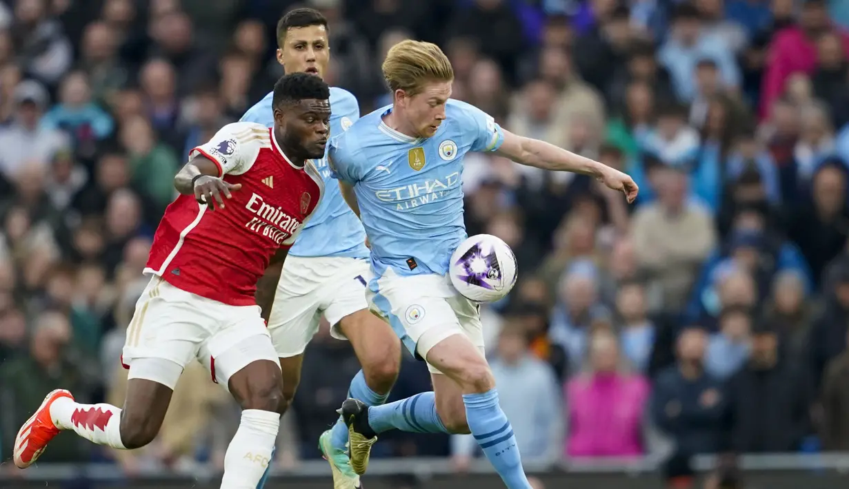 Gelandang Manchester City, Kevin De Bruyne (kanan) menguasai bola dibayangi gelandang Arsenal, Thomas Partey pada laga pekan ke-30 Premier League 2023/2024 di Etihad Stadium, Manchester, Minggu (31/3/2024). (AP Photo/Dave Thompson)
