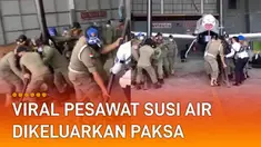 Sejumlah Satpol PP bergotong royong menarik pesawat dan perlengkapannya.