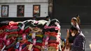 Orang-orang membeli pakaian dari kios-kios yang didirikan di luar gedung bioskop di New Delhi (29/12/2021). Pemerintah Delhi memberlakukan pembatasan fasilitas seperti gedung bioskop, multipleks, dan gym, dan lainya untuk mengekang lonjakan virus corona Covid-19. (AFP Photo/Sajjad Hussain)
