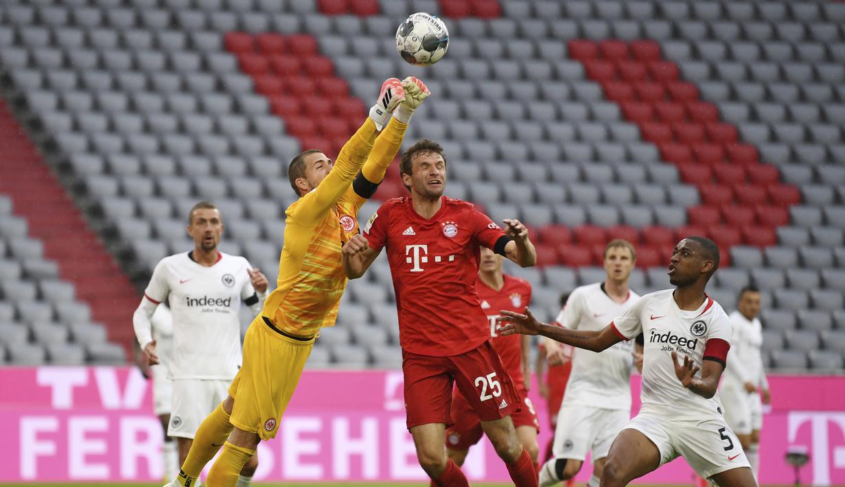 Pemain Bayern Munchen, Thomas Muller, berebut bola dengan kiper Eintracht Frankfurt, Kevin Trapp, pada laga Bundesliga di Allianz Arena, Minggu (24/5/2020). Bayern Munchen menang 5-2 atas Eintracht Frankfurt. (AP/Andreas Gebert)