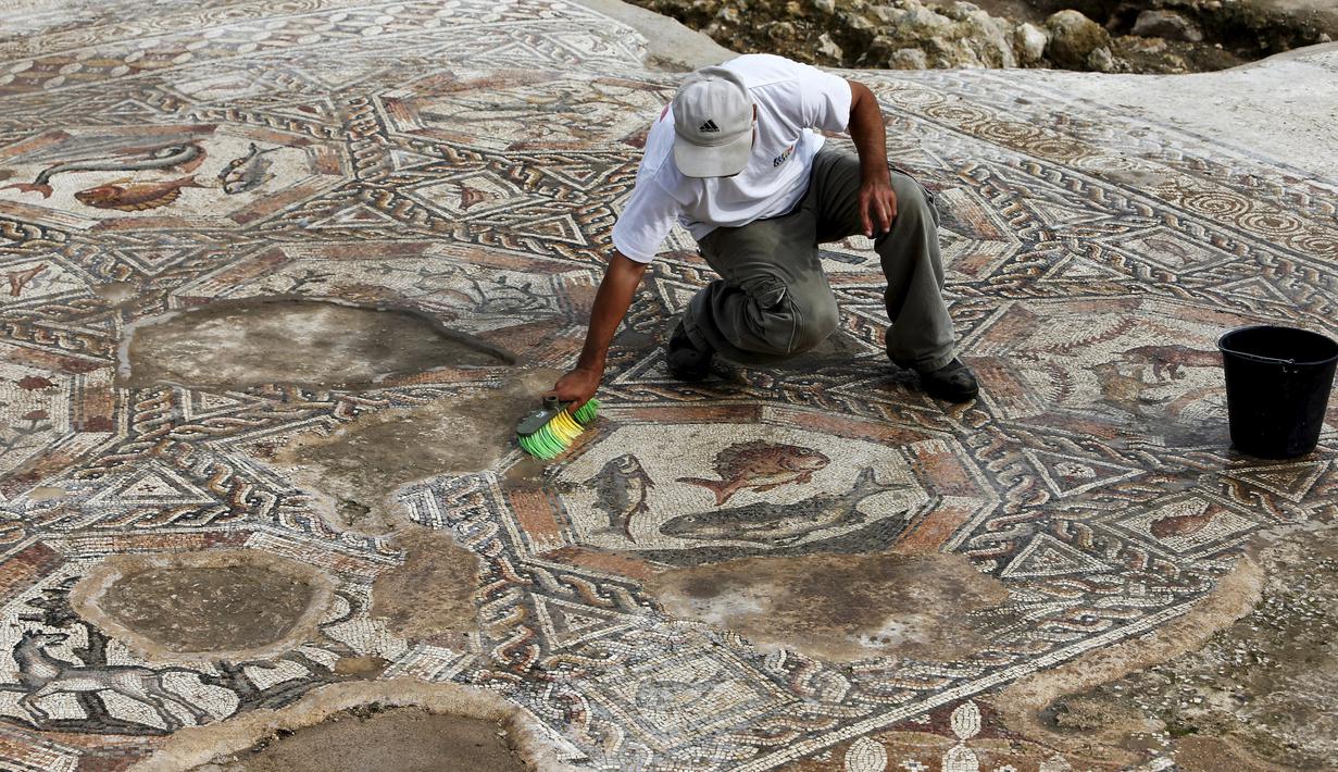 Seorang peneliti sejarah kuno membersihkan sebuah gambar yang ada pada lantai sebuah peradaban pada 1.700 tahun yang lalu di Tel Aviv, Israel, Senin (16/11/2015). Dulunya kota ini merupakan kota yang makmur. (REUTERS/Nir Elias)