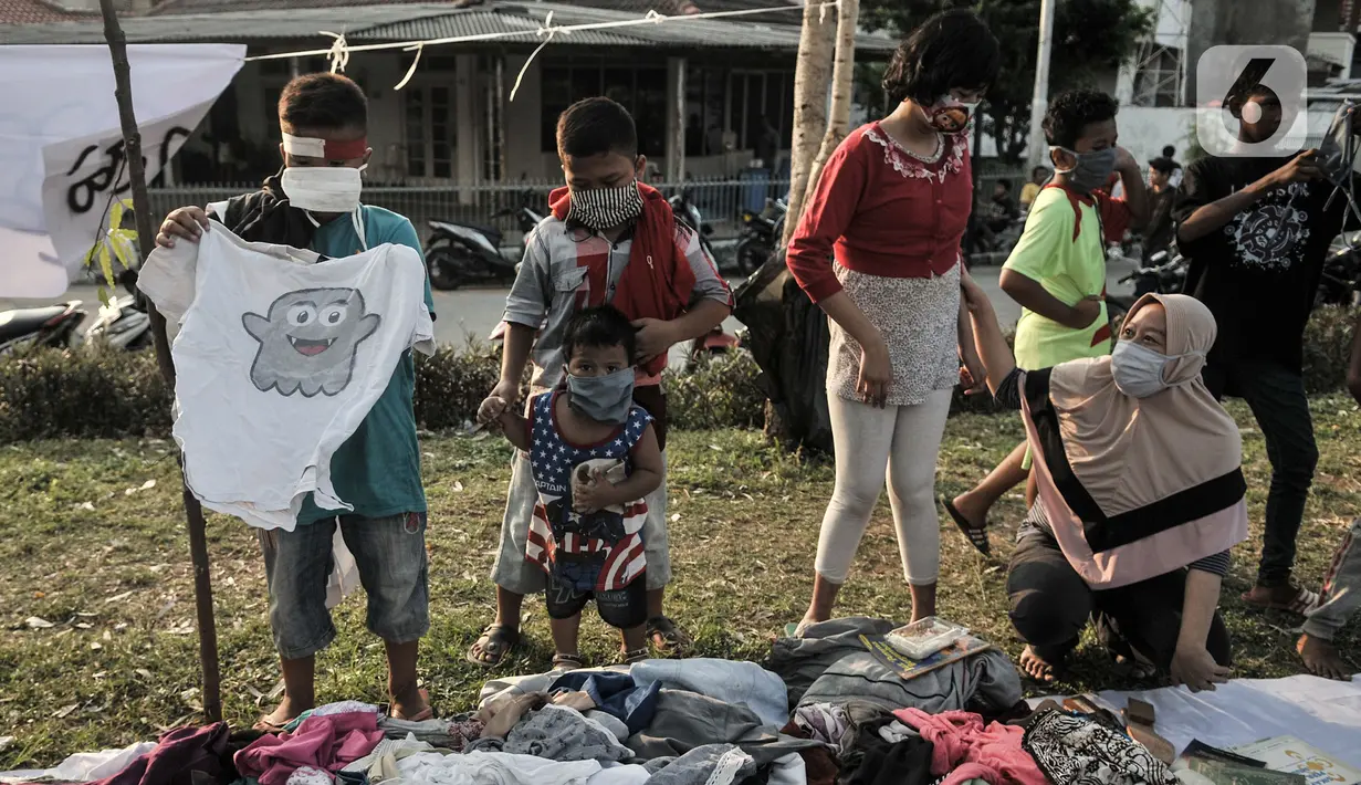 Anak-anak dan orangtua memilih pakaian saat kehadiran Perpustakaan Keliling di kawasan Kampung Melayu, Jakarta, Minggu (16/8/2020). Kegiatan sosial ini menghadirkan latihan tari, donasi pakaian layak, makanan, serta masker. (merdeka.com/Iqbal S. Nugroho)