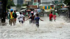 Sejumlah anak berlarian sambil bermain banjir yang merendam kawasan Benhil RT 03 RW 05, Jakarta Pusat, Selasa (21/1). Hujan deras yang mengguyur sejak Selasa dinihari mengakibatkan kawasan tersebut mengalami banjir. (Liputan6.com/Johan Tallo)
