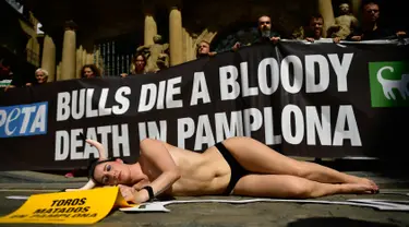 Aktivis yang bertelanjang dada berbaring di jalan saat menggelar protes terhadap adu banteng di Pamplona, Spanyol, Jumat (5/7/2019). Aksi protes ini digelar sehari sebelum pembukaan Festival San Fermin. (AP Photo/Alvaro Barrientos)