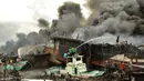 Para pekerja mencoba membantu memadamkan api di kapal nelayan di Pelabuhan Benoa, Denpasar, Bali, Senin (9/7). Kebakaran semakin membesar karena angin cukup kencang. (SONNY TUMBELAKA/AFP)