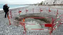Pengunjung mengambil gambar kawah misterius yang dikelilingi pagar besi di Pantai Lido, Nice, Prancis, Kamis (1/2). Pihak berwenang mengatakan, lubang yang mulai terbentuk pada Rabu itu tidak menimbulkan bahaya bagi keamanan publik. (VALERY HACHE/AFP)