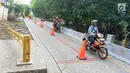 Pengendara motor melintasi akses pintu masuk dan keluar Universitas Indonesia di Depok, Jawa Barat, Selasa (16/7/2019). Penerapan uji coba sistem masuk parkir UI berbayar yang menyebabkan kemacetan panjang membuat gerbang tiket pembayaran kembali dinonaktifkan. (Liputan6.com/Immanuel Antonius)