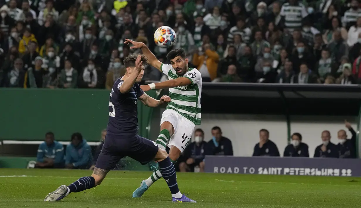Bek Sporting Lisbon Ricardo Esgaio melakukan tembakan ketika bek Manchester City John Stones pada leg pertama 16 besar Liga Champions 2021/2022 di Estadio Jose Alvalade, Rabu (16/2/2022) dini hari WIB.  Manchester City mampu mengalahkan tuan rumah Sporting CP 5-0. (AP Photo/Armando Franca)