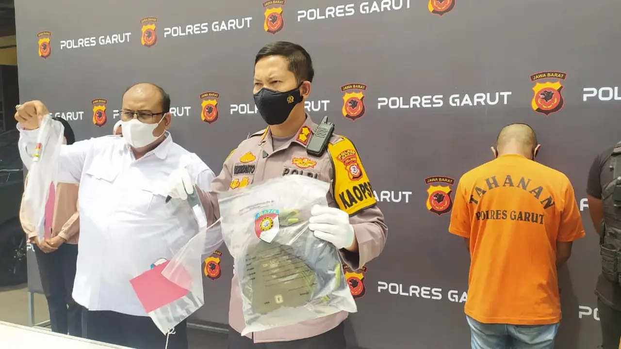 Kepolres Garut AKBP Wirdhanto Hadicaksono, menunjukan tas dan barang bukti lainnya yang digunakan tersangka dalam aksi laporan palsu korban begal motor, dalam rilis perkara di Mapolres Garut, Senin (11/10/2021).