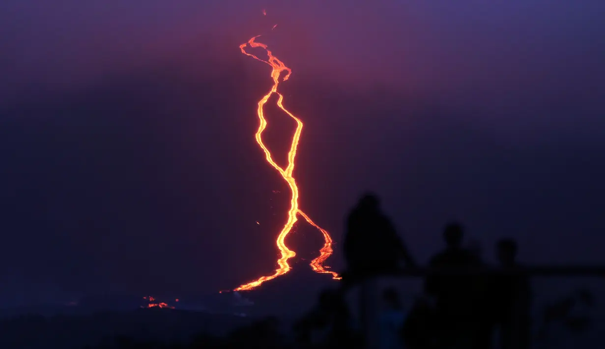 Warga melihat guguran lava pijar yang keluar dari gunung api Piton de la Fournaise atau Peak of the Furnace di Pulau Reunion, Samudera Hindia, Prancis, Selasa (13/8/2019). Letusan Piton de la Fournaise berlanjut hingga hari ketiga. (Richard BOUHET/AFP)