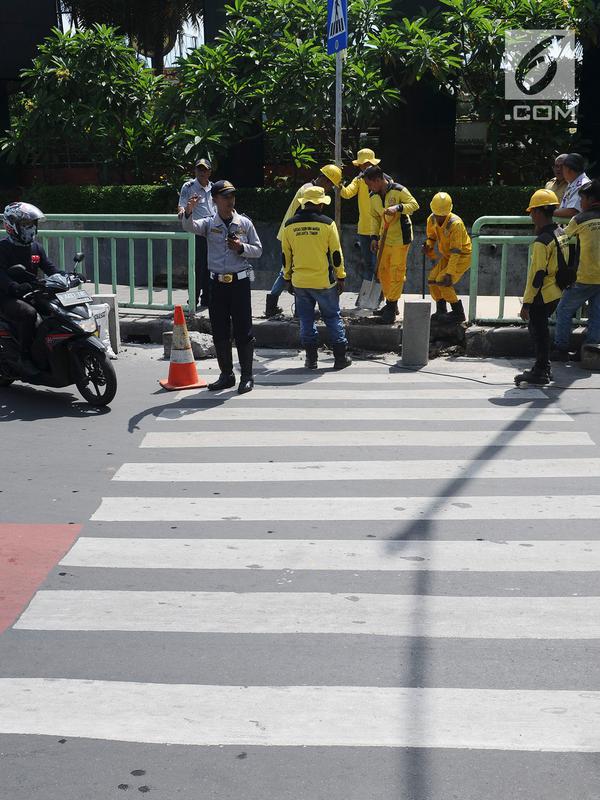 Pengendara motor melintasi saat pekerja sedang membongkar pagar pembatas besi di kawasan Pinang Ranti, Jakarta, Senin (11/2). Zebra cross itu sempat jadi perbincangan lantaran terhalang oleh pagar besi hijau setinggi 1 meter (Liputan6.com/Herman Zakharia)