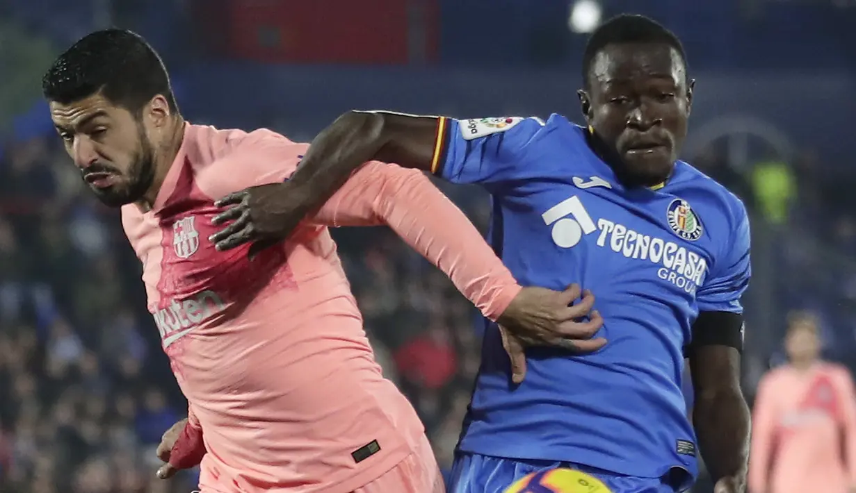 Striker Barcelona, Luis Suarez, berebut bola dengan pemain Getafe, Djene, pada laga La Liga di Stadion Alfonso Perez, Minggu (6/1). Barcelona menang 2-1 atas Getafe. (AP/Manu Fernandez)