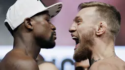 Petarung MMA, Conor McGregor dan petinju Floyd Mayweather Jr saat sesi timbang berat badan di Las Vegas, Jumat (25/8/2017). Keduanya akan bertarung pada Minggu (27/6/2017) di T-Mobile Arena, Las Vegas, Amerika Serikat. (AP/John Locher)