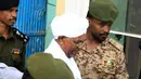 Mantan Presiden Sudan, Omar al-Bashir, dikawal saat keluar dari penjara menuju kantor kejaksaan dalam penyelidikan korupsi di ibu kota Khartoum, Minggu (16/6/2019). Jaksa mengatakan timbunan mata uang asing ditemukan dalam karung gandum di rumah Bashir saat ia dikudeta. (Yasuyoshi CHIBA/AFP)