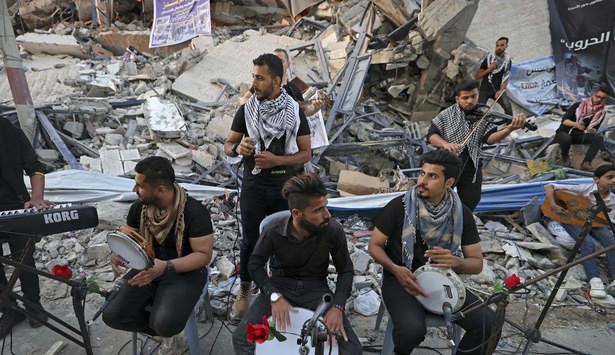 Musisi Palestina tampil di puing-puing Menara Hanadi di Kota Gaza (2/6/2021). Acara diselenggarakan oleh Komite Pemuda dan Kebudayaan Palestina lebih dari seminggu setelah gencatan senjata mengakhiri 11 hari permusuhan antara Israel dan Hamas. (AFP Photo/Mohammed Abed)