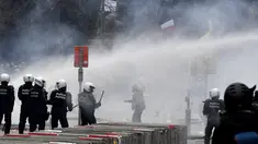 Polisi menembakkan water cannon ke arah pengunjuk rasa saat demonstrasi menentang tindakan Covid-19 di Brussel, Minggu (23/1/2022). Pengunjuk rasa berkumpul di ibu kota Belgia mengkritik dan menolak aturan pembatasan akibat COVID-19, salah satunya terkait vaksinasi. (AP Photo/Geert Vanden Wijngaert)