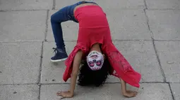 Seorang gadis berdandan sebagai "Catrina" atau wanita kerangka menunggu dimulainya Prosesi Grand Catrinas, bagian dari perayaan Day of The Dead, di Mexico City, Minggu (22/10). Acara ini untuk mengenang mendiang kerabat dan sahabat. (AP/Rebecca Blackwell)