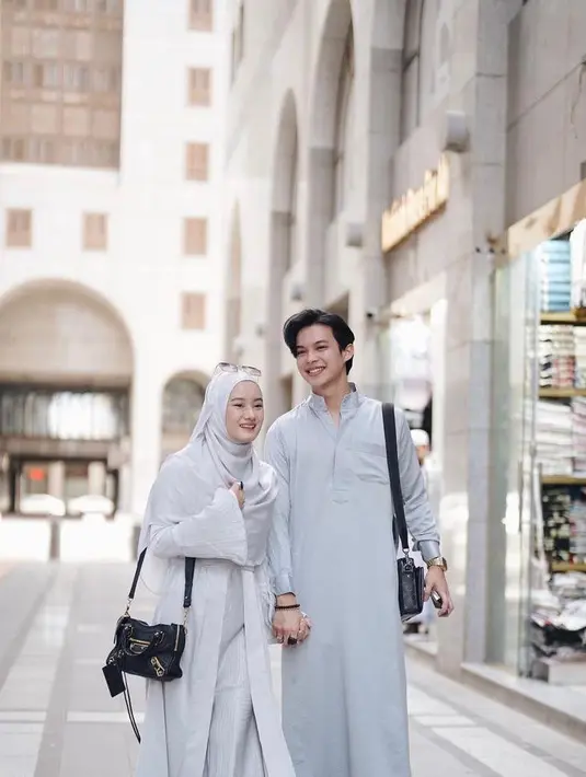Dinda tampil menawan mengenakan gamis lengan terompet dipadukan hijab menutupi dada, serta sling bag hitam. Sementar Rey mengenakan thawb yang juga membawa sling bag hitamnya. (Instagram/dindahw).