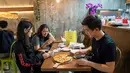 Pengunjung memotong pizza rasa durian di kafe Mao Shan Wang di Singapura (26/1). Restoran yang menyediakan beragam aneka rasa durian ini telah menarik banyak pengunjung untuk datang mencicipi buah durian di kafe tersebut. (AFP Photo/Nicholas Yeo)