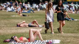 Sejumlah warga Inggris berjemur di atas rumput sambil menikmati sinar matahari di Green Park, London, Senin (25/6). Pada Juli 2018, suhu di ibu kota London tercatat 29.1 derajat Celcius dan diprediksi akan mencapai 30 derajat Celcius. (AFP/Tolga Akmen)