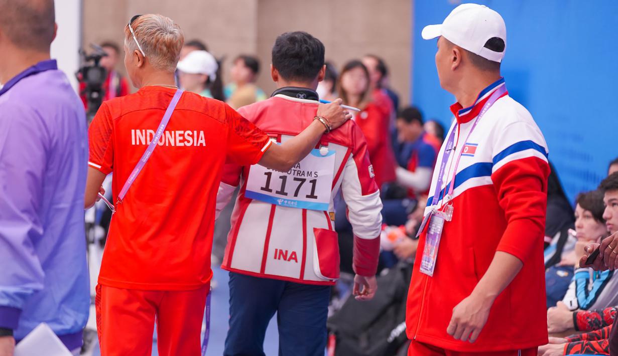 Petembak Indonesia, Muhammad Sejahtera Dwi Putra didampingi ofisial tim usai memenangi lomba nomor perorangan 10 meter running target putra cabang menembak Asian Games Hangzhou 2022 di Fuyang Yinhu Sports Centre, Hangzhou, China, Senin (25/9/2023). (NOC Indonesia)