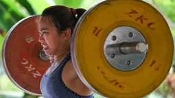Atlet angkat besi Olimpiade Filipina, Hidilyn Diaz mengangkat beban saat berlatih di Jasin, kota Malaka, pada 21 Mei 2021. Diaz yang terpaksa tinggal di Malaysia bertekad situasi tidak akan menghalangi cita-citanya untuk menjadi peraih medali emas Olimpiade pertama dari Filipina. (Mohd RASFAN/AFP)