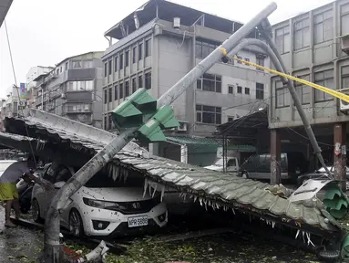 Seorang pria melihat mobil yang rusak akibat angin kencang Topan Soudelor di Taipe, Taiwan, (8/8/2015). Empat orang tewas akibat peristiwa angin kencang Topan Soudelor dan hujan deras.  (REUTERS/Pichi Chuang)