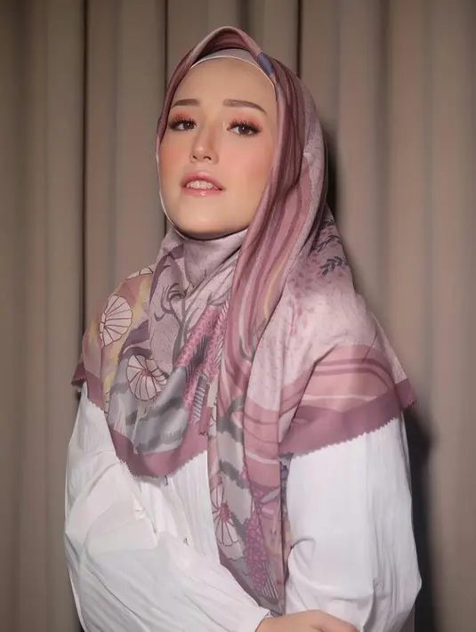 Hijab segi empat satin yang kamu bentuk jadi loose akan memberikan kesan tampilan yang mewah. Buat salah satu sisi hijab lebih pendek, dan tarik sisi hijab yang panjang ke samping. (Instagram.com/adeliapasha).