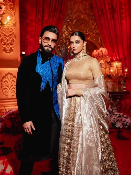 Deepika Padukone hadir bersama sang suami, Ranveer Singh. Sementara Ranveer mengenakan sherwani hitam dengan sedikit warna biru di dadanya, Deepika mengenakan lehenga emas dan perak, dipadukan dengan perhiasan emas. [@pinkvilla]