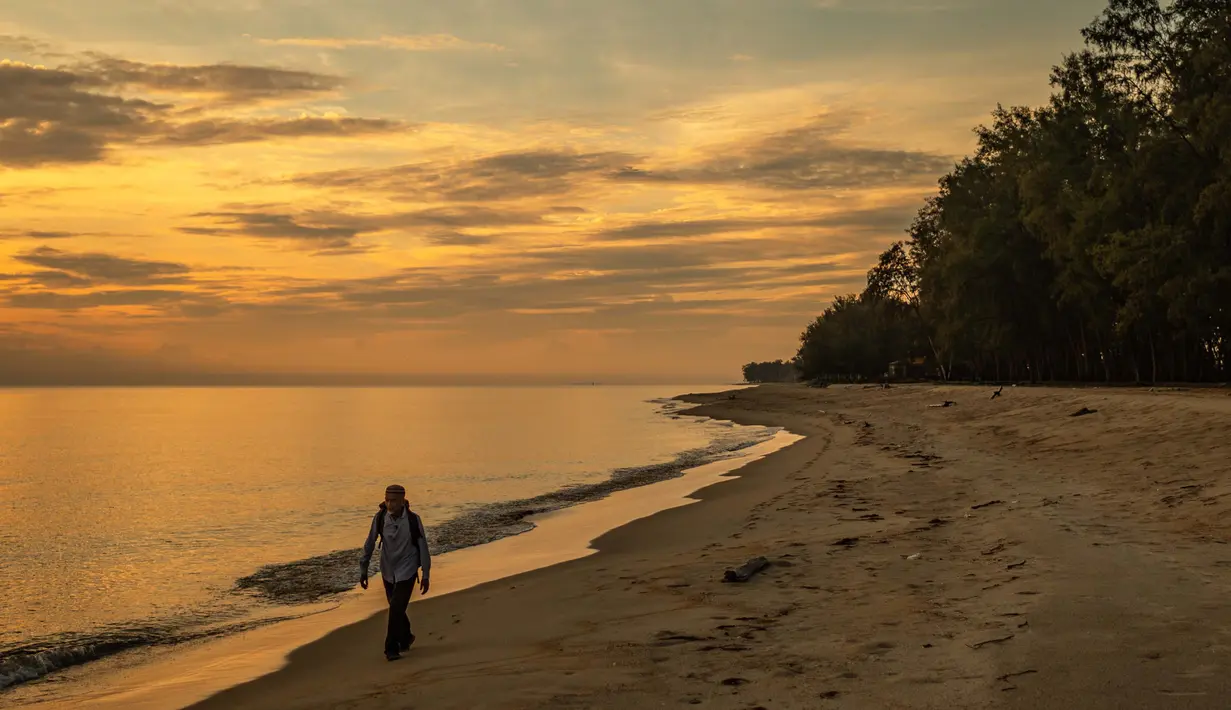 Tengku Mohamad Ali Mansor berjalan menyusuri pantai saat matahari terbit saat dia mencari botol kaca di desa Mangkuk di distrik Setiu negara bagian Terengganu Malaysia timur pada 12 September 2020.  (AFP/Mohd Rasfan)