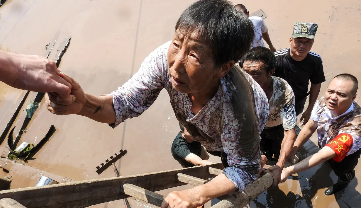 Pejabat desa mengevakuasi penduduk dari daerah banjir setelah hujan lebat di Dazhou di provinsi Sichuan barat daya China (12/7/2021). Banjir akibat hujan lebat melanda sejumlah wilayah di China. (AFP/STR)