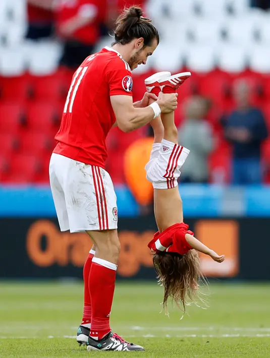 Gareth Bale merayakan kemenangan atas Irlandia Utara di babak 16 besar Euro 2016 di Parc des Princes bersama putrinya, Paris, Prancis, Minggu (26/6). (REUTERS/ Christian Hartmann)