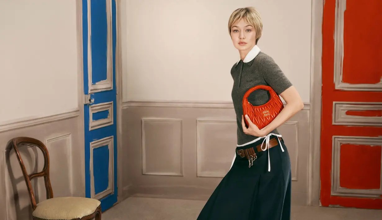 Sementara dalam gaya lain, Gigi mengenakan sweater olive dengan rok hijau terang dan sandal anyaman, dipadukan tas putih mungil yang memberi kesan lebih soft dan feminin. [Dok/Miu Miu].