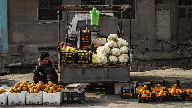 Pedagang kaki lima memajang sayuran dan buah-buahan untuk dijual di kota Raqa, bekas ibu kota ISIS, di Suriah utara pada 20 Desember 2020. Raqqa menjadi saksi terusirnya anggota kelompok militan tersebut oleh Pasukan Demokratik Suriah pada Oktober 2017 lalu. (Photo by Delil SOULEIMAN / AFP)