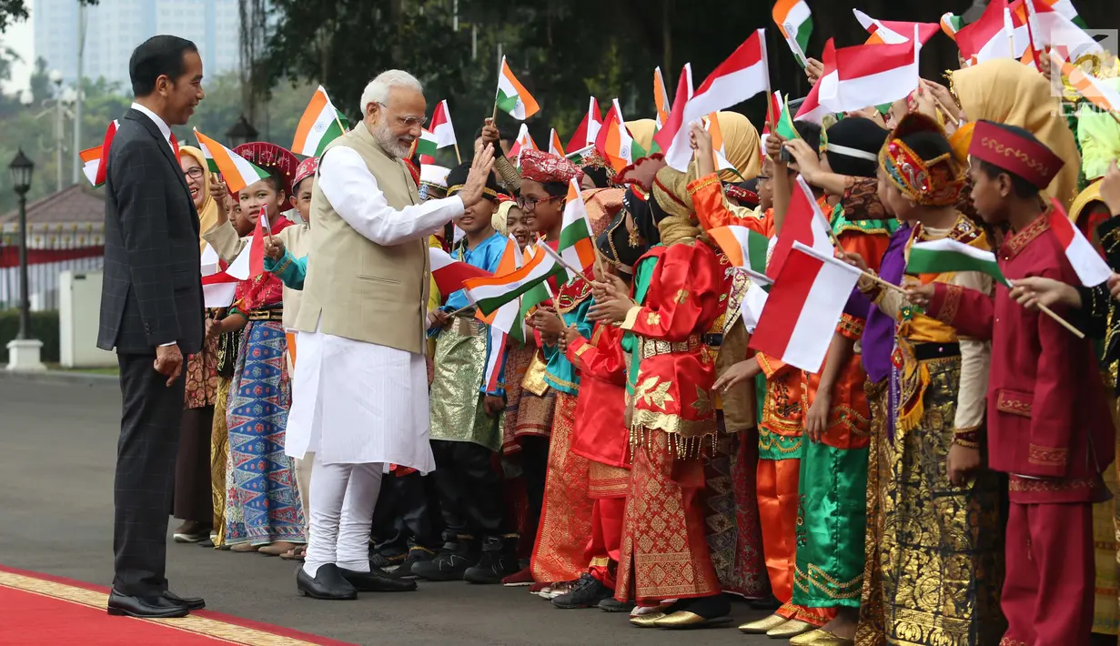 Perdana Menteri (PM) India, Narendra Modi didampingi Presiden Joko Widodo (Jokowi) bersalaman dengan murid Sekolah Dasar berpakaian adat Indonesia dalam upacara penyambutan di Istana Merdeka, Jakarta, Rabu (30/5). (Liputan6.com/Angga Yuniar)