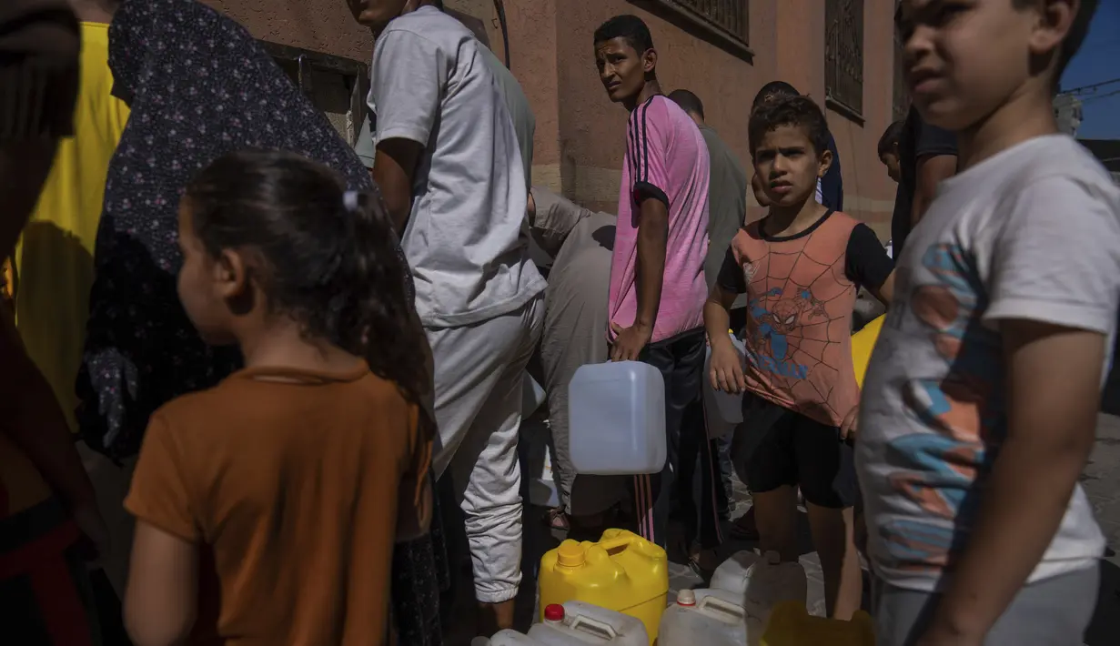 Warga Palestina, termasuk anak-anak, mengambil air dari keran air di tengah kekurangan air minum, di Khan Younis, Jalur Gaza, Minggu, 15 Oktober 2023. (AP Photo/Fatima Shbair)
