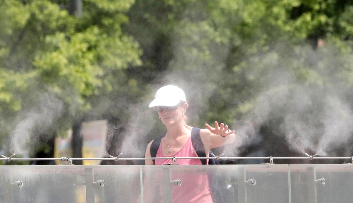 Pengunjung berjalan melalui kabut air untuk mendinginkan diri di Lapangan Gwanghwamun, Seoul, Korea Selatan, Senin (23/7). (AP Photo/Lee Jin-man)