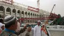 Calon jemaah haji foto bersama dengan latar berlakang crane yang roboh di Masjidil  Haram, Kota Mekah,  Arab Saudi (9/12/2015). Sebanyak 107 calon jemaah haji meninggal dunia akibat crane jatuh karena cuaca buruk. (AFP PHOTO / STR)