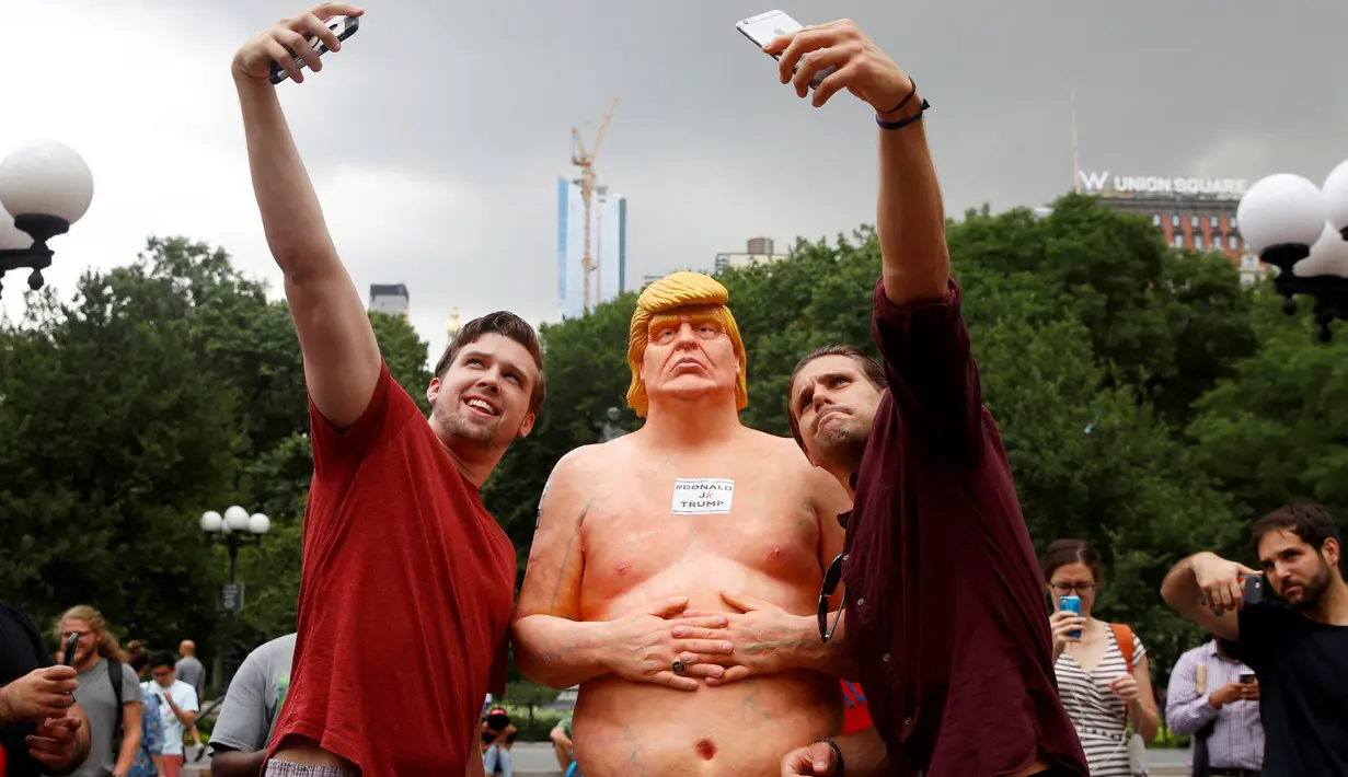 Dua warga berselfie dengan patung Donald Trump tanpa busana yang dipajang di Union Square Park, AS, Kamis (18/8). Patung Capres AS dari Partai Republik ini juga dipajang di San Francisco, Los Angeles, Cleveland, dan Seattle. (REUTERS/Brendan McDermid)