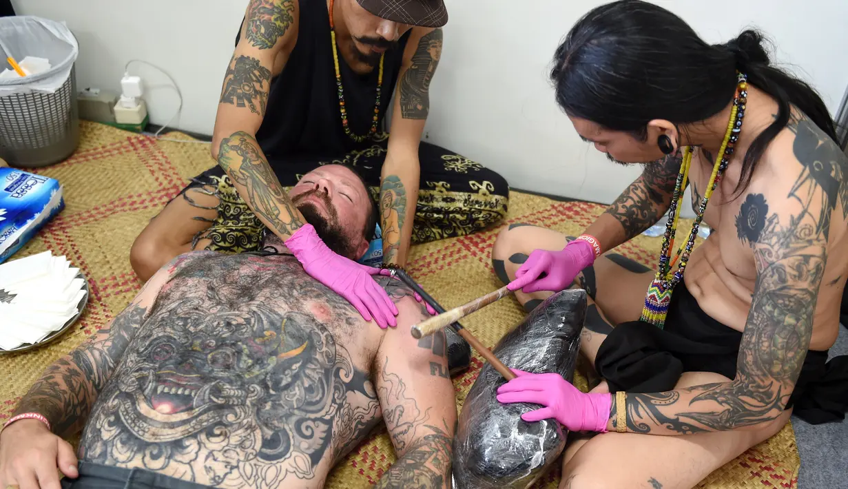 Seniman saat membuat tato pengunjung pria saat acara Bali Tattoo Expo 2017 di pulau resor Indonesia, Denpasar, Bali (12/5). Acara ini digelar selama 3 hari, mulai (12/5/2017) sampai (14/5/2017). (AFP Photo/Sonny Tumbelaka)