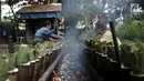 Pak Pian ditemani Pak Bambang saat memasak lemang di sebuah tanah kosong di Jakarta, Minggu (27/5). Memasuki bulan Ramadan, produksi makanan tradisional Melayu berbahan dasar ketan tersebut terus meningkat. (Merdeka.com/Iqbal S Nugroho)