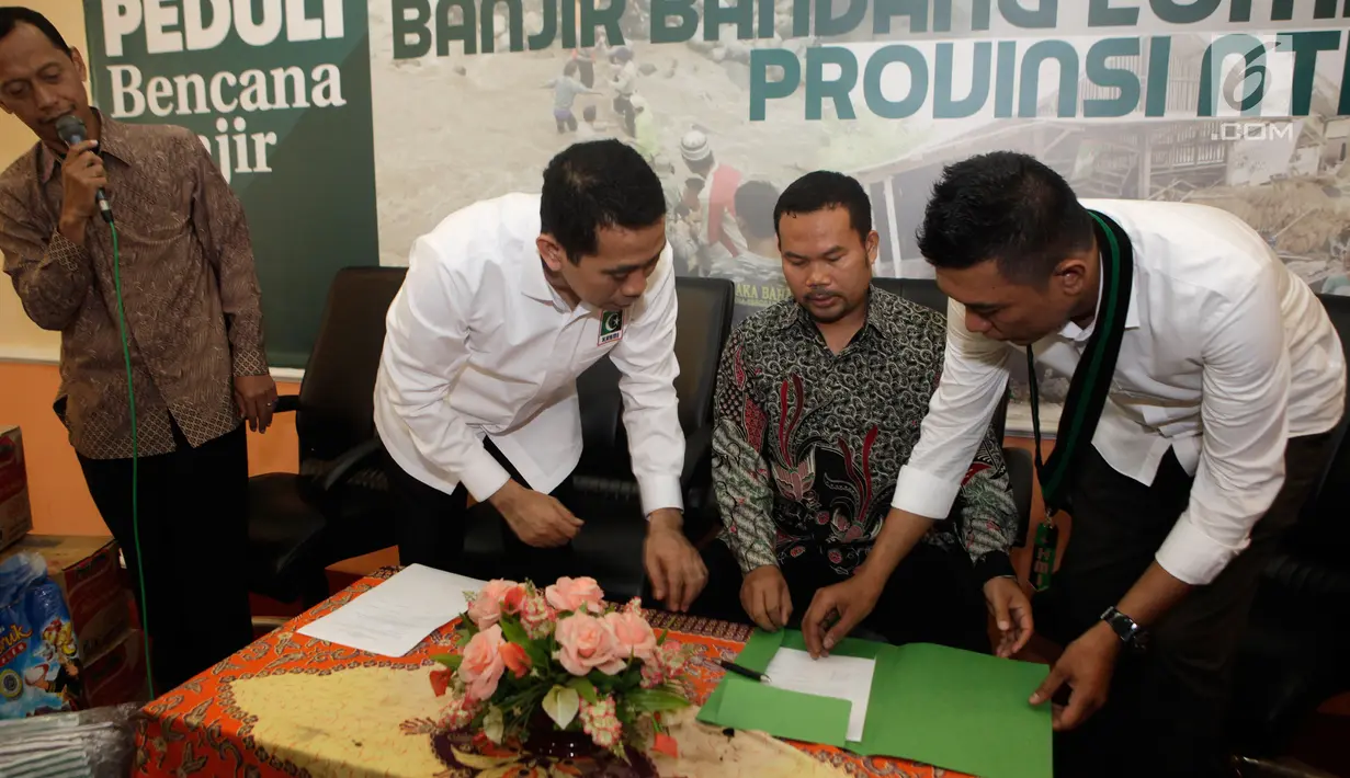 Presidium Majelis Nasional KAHMI, Kamrussamad, Ketua MD Lombok Timur NTT, Ahmad Roji dan Muhammad Ridal  saat menandatangani serah terima bantuan korban banjir di Lombok Timur, Jakarta, Selasa (21/11). (Liputan6.com/Pool/KAHMI)
