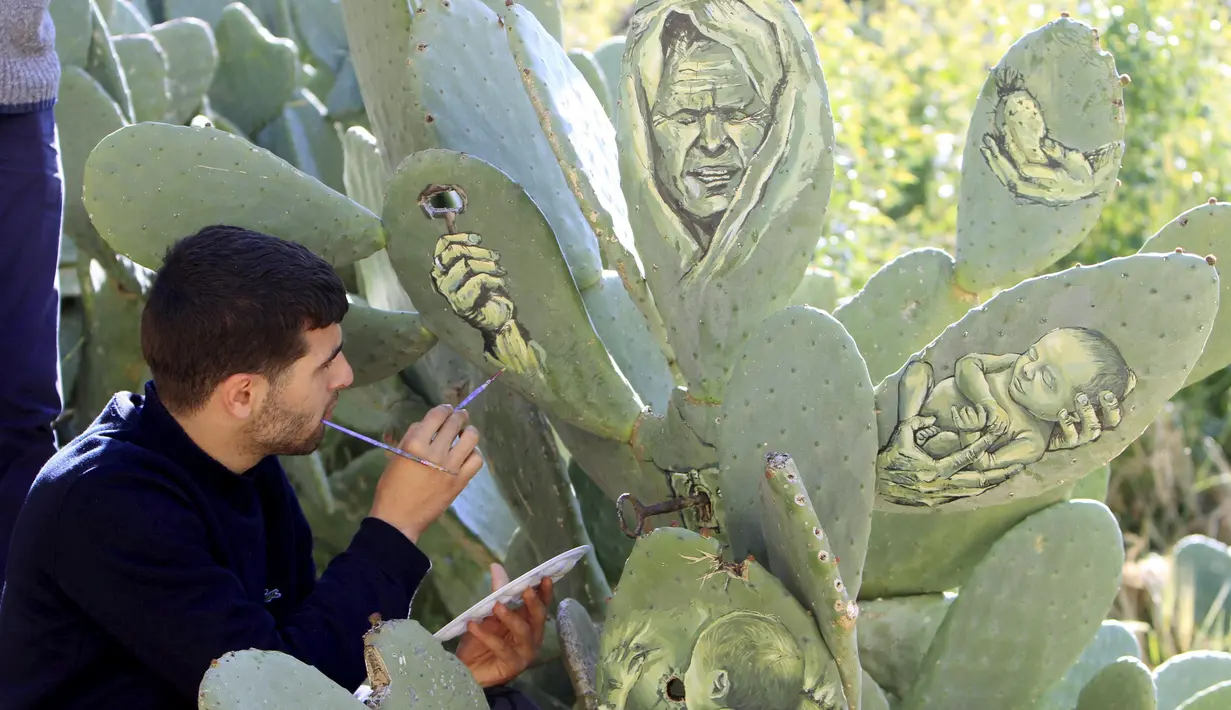Seniman muda Palestina, Ahmad Yasin saat melukis tanaman kaktus di desa Tepi Barat Aseera Ashmaliya dekat Nablus, (31/3).Berbagai gambar unik dituangkan Ahmad Yasin kedalalam sejumlah tangkai kaktus.  (REUTERS / Abed Omar Qusini)